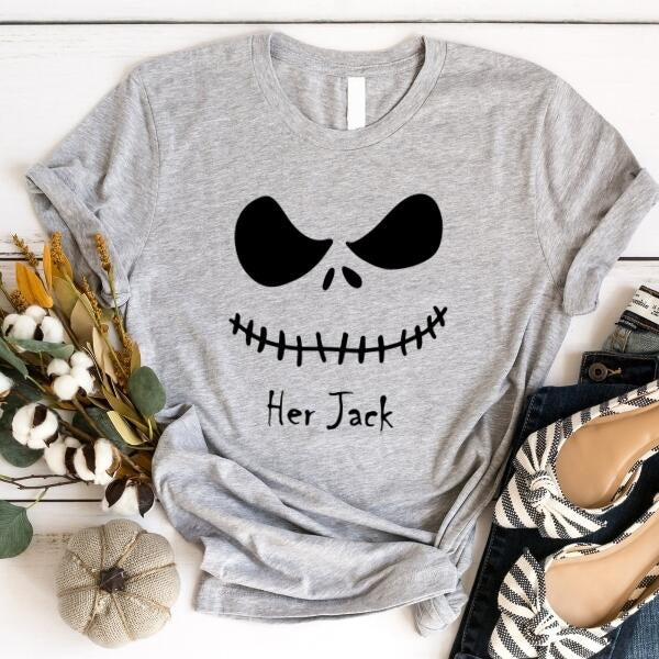 Gray t-shirt with a black skull design and 'Her Jack' text on a white surface with decorative items.