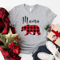 May include matching family t-shirts featuring a Christmas bear design, laid flat with festive decorations and greenery.