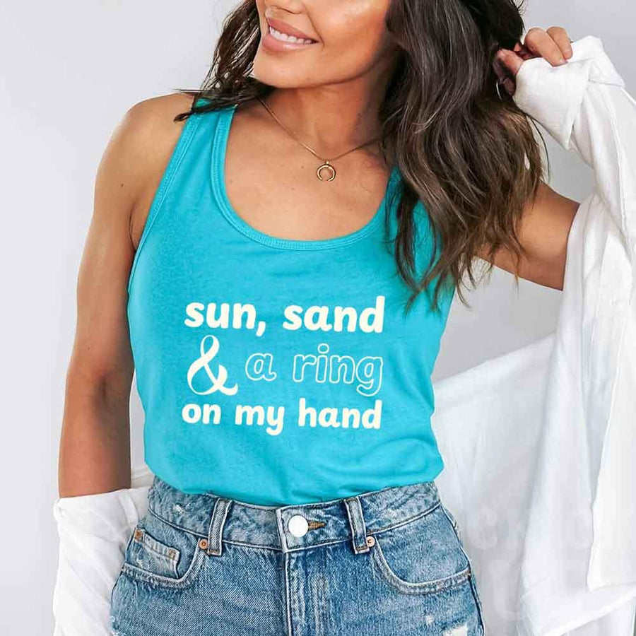 May include a Tahiti Blue tank top with the phrase “Sun Sand & A Ring On My Hand” in a stylish summer font, ideal for brides.