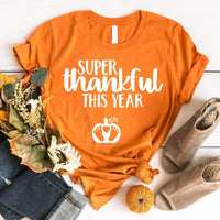 May include a unisex t-shirt with the phrase ‘Super Thankful For This Year,’ printed in a warm fall color palette, styled for Thanksgiving and autumn wear.