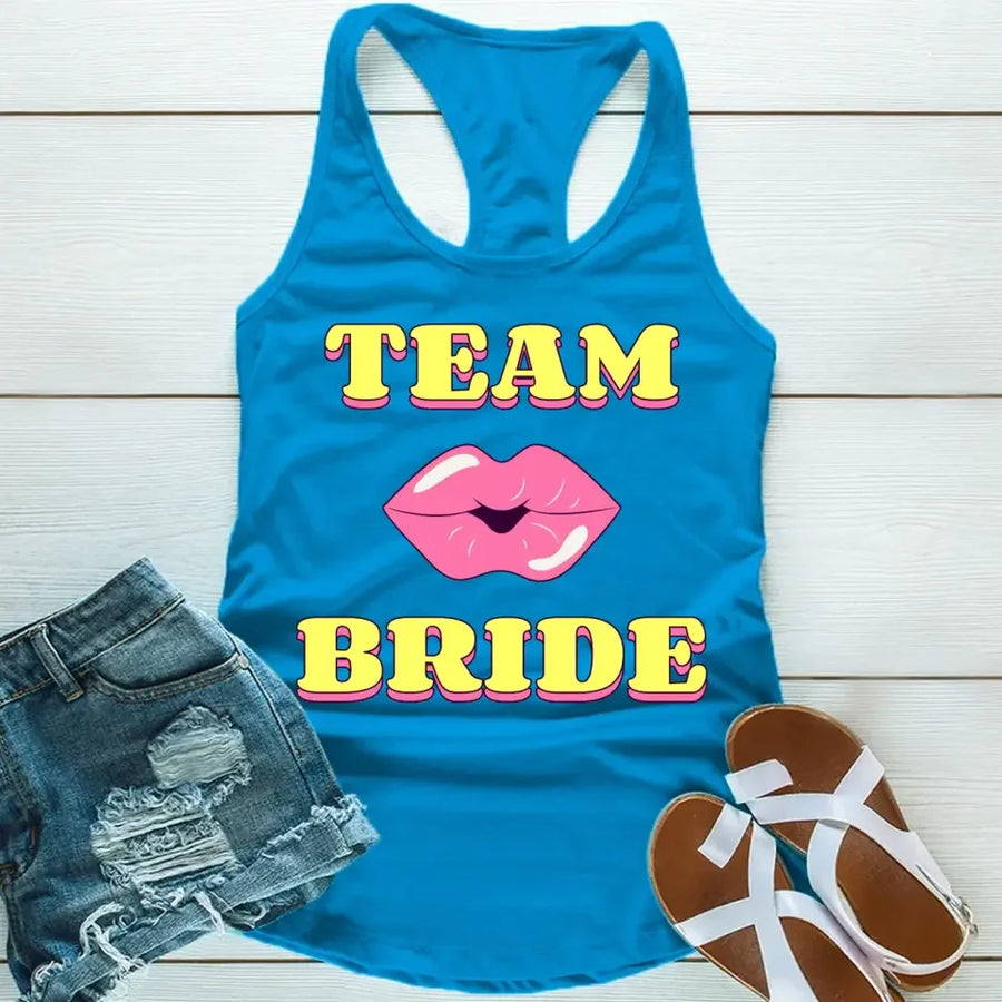A blue tank top with 'TEAM BRIDE' text and a heart symbol replacing the word 'TEAM'. The tank top is displayed alongside denim shorts and white sandals, suggesting a casual outfit for a bachelorette party.