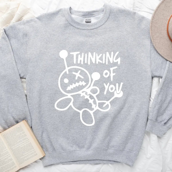 May include a t-shirt featuring the phrase “Thinking About You” in a clean or artistic font style. The design may use soft or minimalist colors, conveying a thoughtful, sentimental, or romantic message suitable for casual wear.