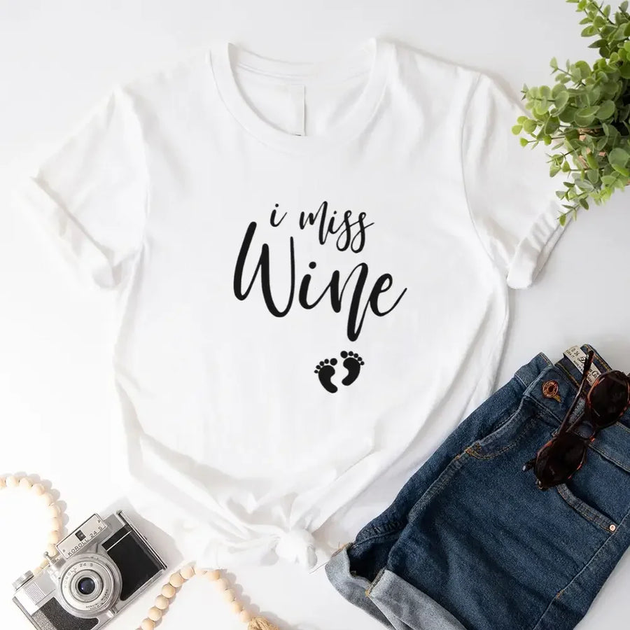 White custom tee with 'I miss wine' text and baby footprints, styled with denim shorts.