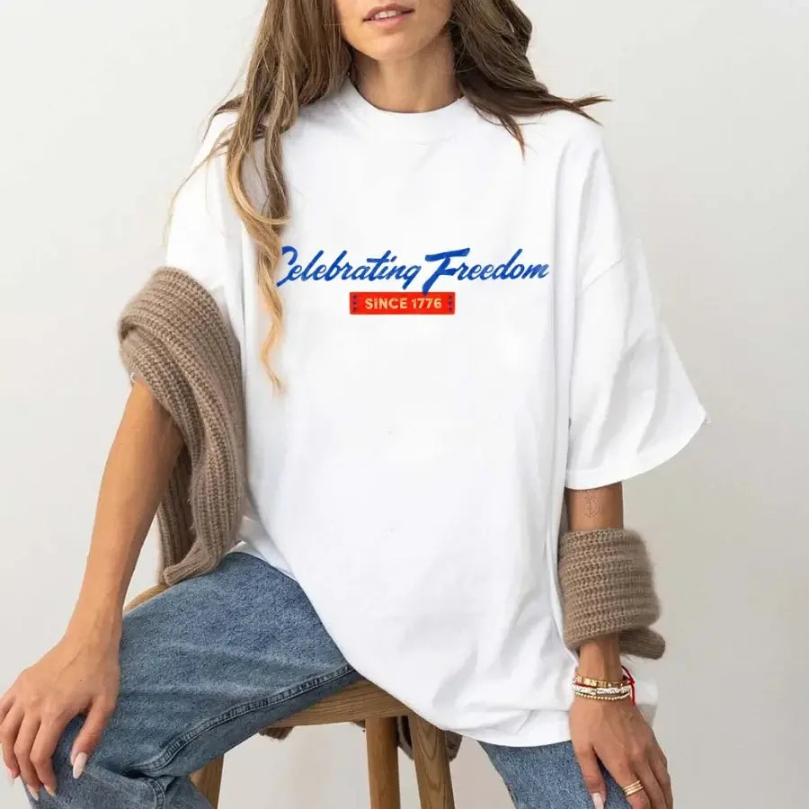 Person wearing a white t-shirt with 'Celebrating Freedom' text, sitting on a chair.