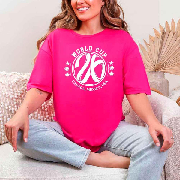 May include a person wearing a Heliconia colored 2026 World Cup T-shirt featuring bold soccer graphic and relaxed fit.