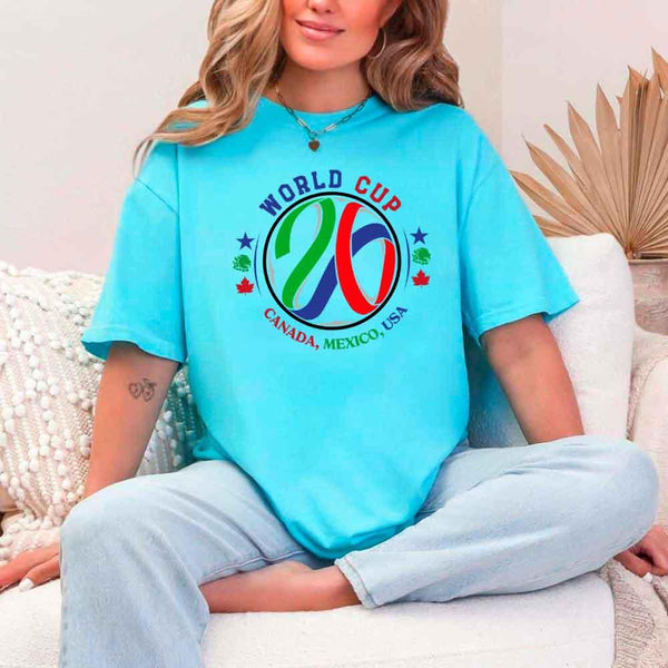 May include a person wearing a Turquoise colored 2026 World Cup T-shirt featuring bold soccer graphic and relaxed fit.