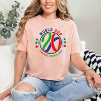 May include a person wearing a Peach colored 2026 World Cup T-shirt featuring bold soccer graphic and relaxed fit.