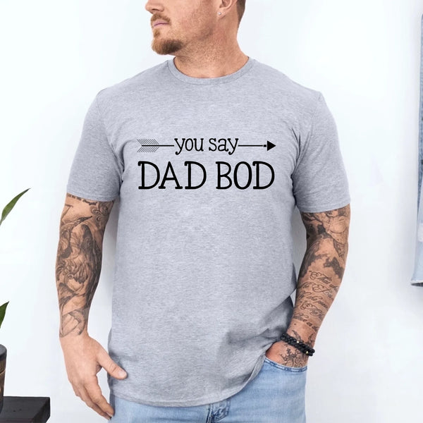 May include a person wearing a funny dad graphic t-shirt with the phrase “You Say Dad Bod, I Say Father Figure”.